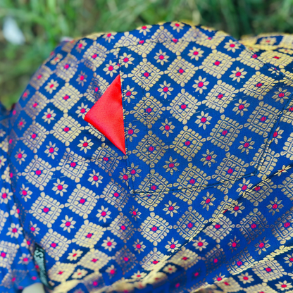 Blue fabric with gold and red pattern, featuring a red triangle on a blurred green background